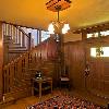 View of restored entry hall shows original stair and 58" wide entry door.  Note the Greenes' art glass in door.  We employed their trailing vine motif for new firebox header.  Photo is coutesy of Popular Woodworking.