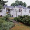 View from backyard before renovation.  Hipped roofs met at a dinky 4' long ridge.  Recessed back door made kitchen dark and limited the view.  Small-scale details were missing, and the house looked stripped.